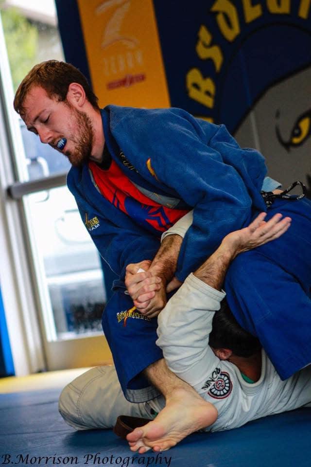 Young man practicing Brazilian Jiu-Jitsu techniques with a partner at Absolute Jiu-Jitsu Academy.