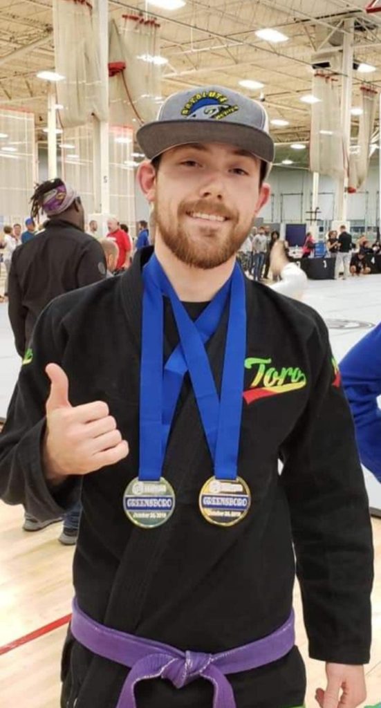 Medal-winning BJJ practitioner at Absolute Jiu-Jitsu Academy in tournament.