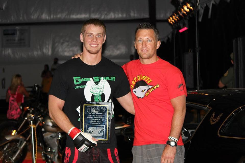 Young male jiu-jitsu athlete holding championship plaque at Absolute Jiu-Jitsu Academy.