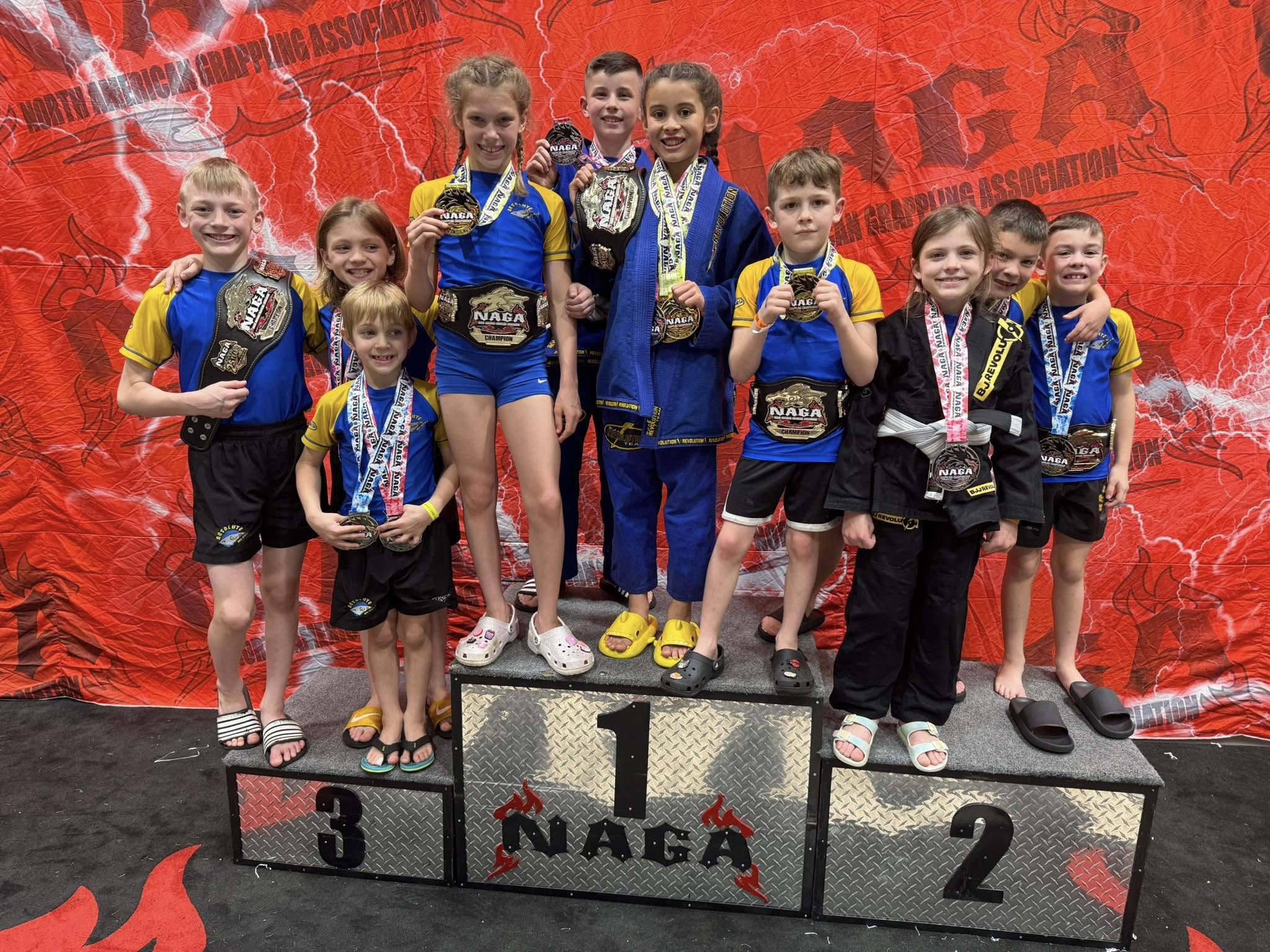 Young martial artists showcase their medals at NAGA competition.