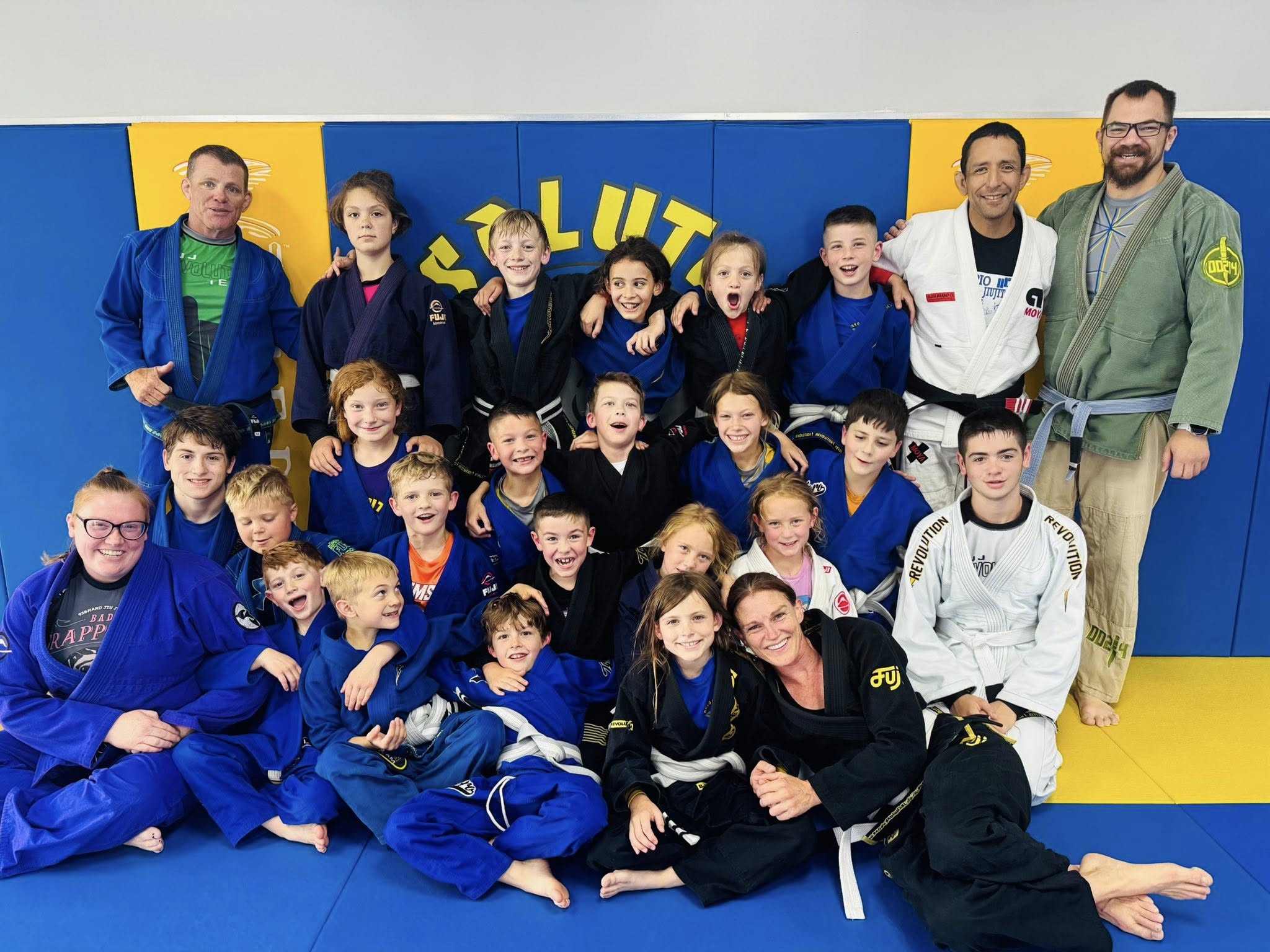 Young students and coaches celebrating after training on the mat.