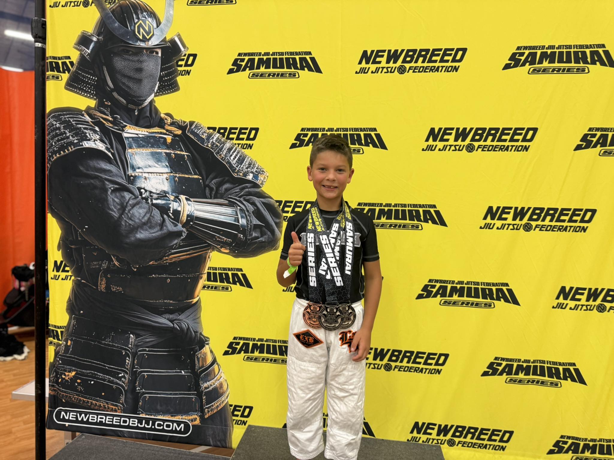 Young athlete celebrating victory with medals and a thumbs-up pose.