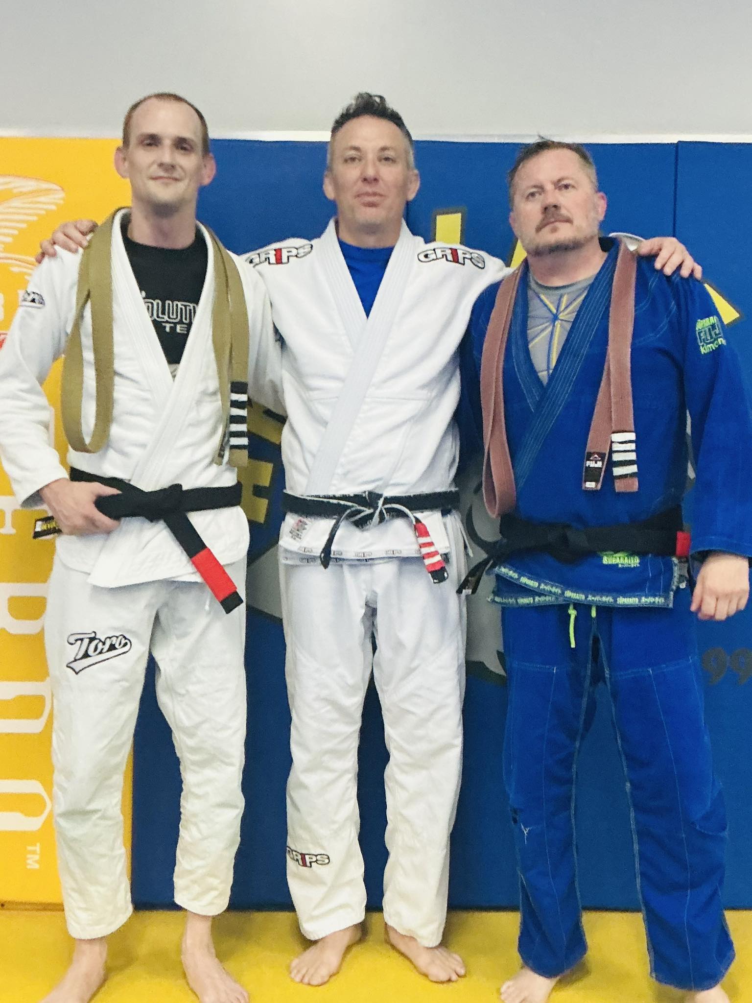 BJJ practitioners in gi with belts at Absolute Jiu-Jitsu Academy, highlighting training and skill development.
