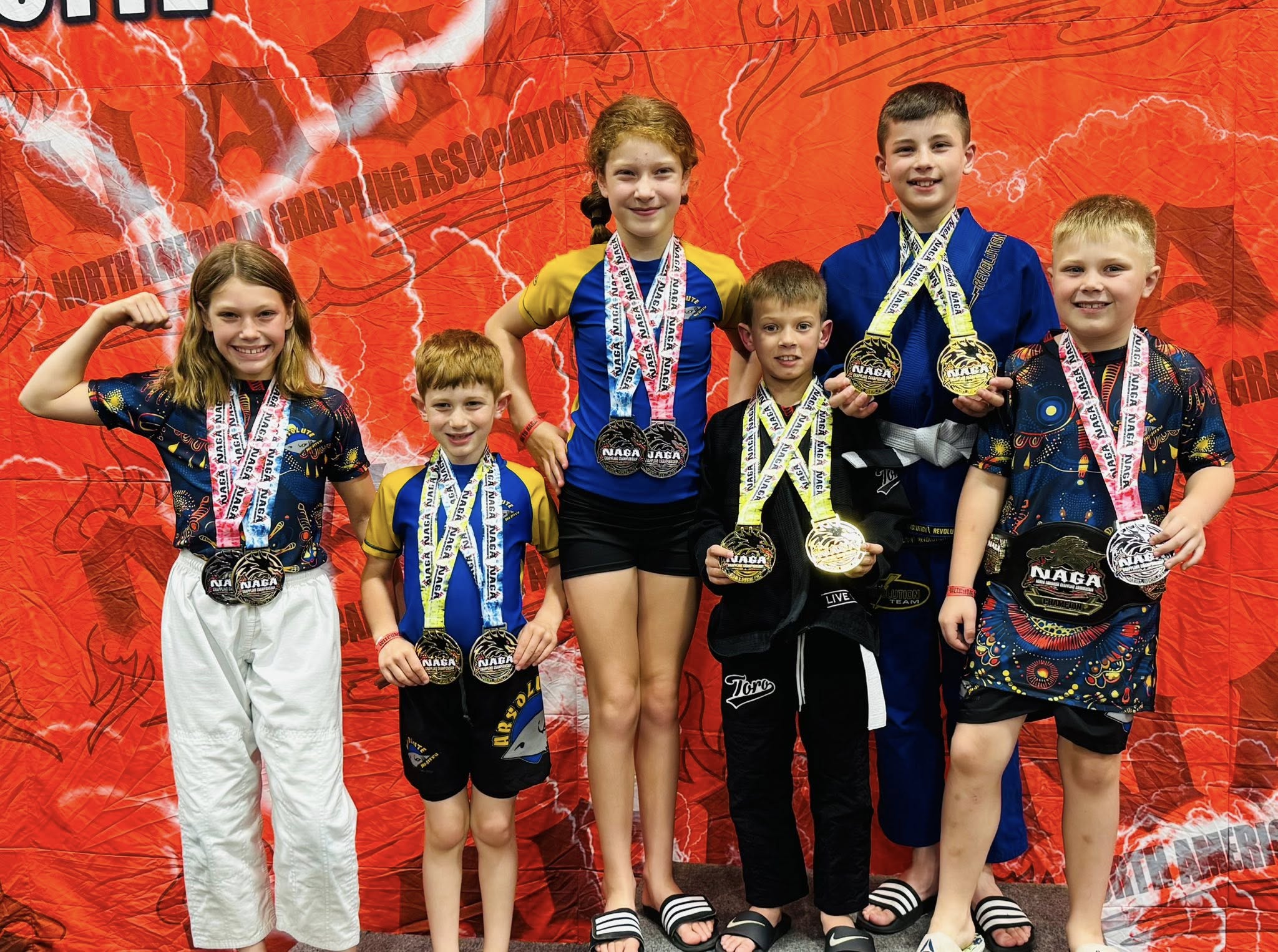 Kids jiu-jitsu athletes with medals at competition.