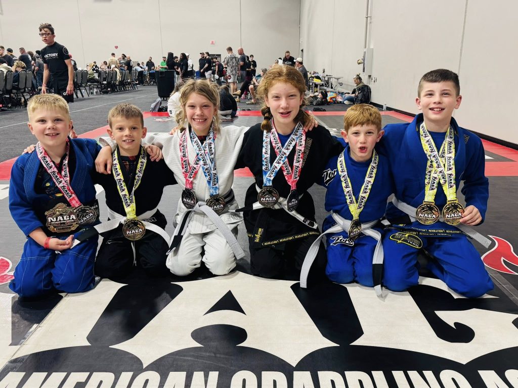 Young martial artists celebrate their victory at Absolute Jiu-Jitsu Academy competition.